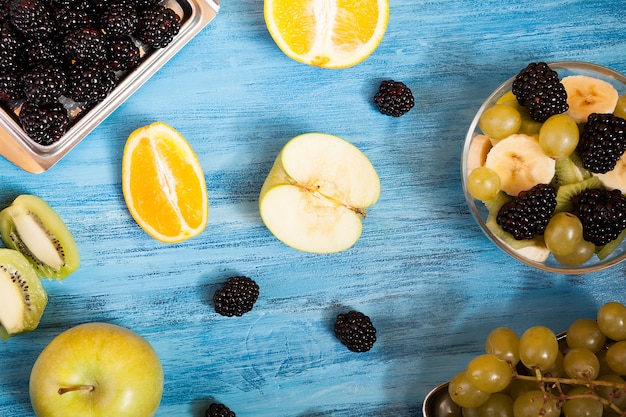 사진 스튜디오의 파란색 책상 위에 얇게 썬 과일과 베리. 천연 다과 열대 영양