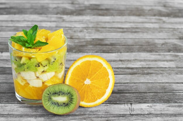 Sliced fruits in a glass on a wooden background