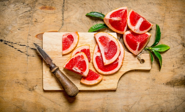 Sliced grapefruit on wooden Board with leaves on wooden table. Top view