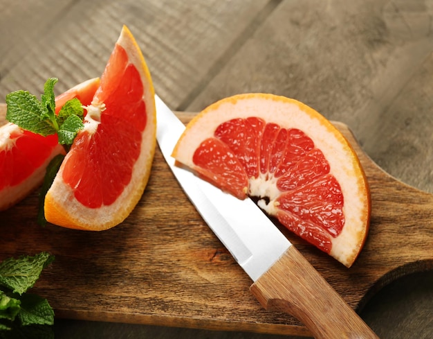 Sliced grapefruits with mint on wooden background close up