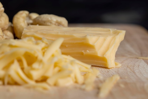 Sliced and grated hard cheese with cashew nuts cow's milk cheese next to peeled cashews