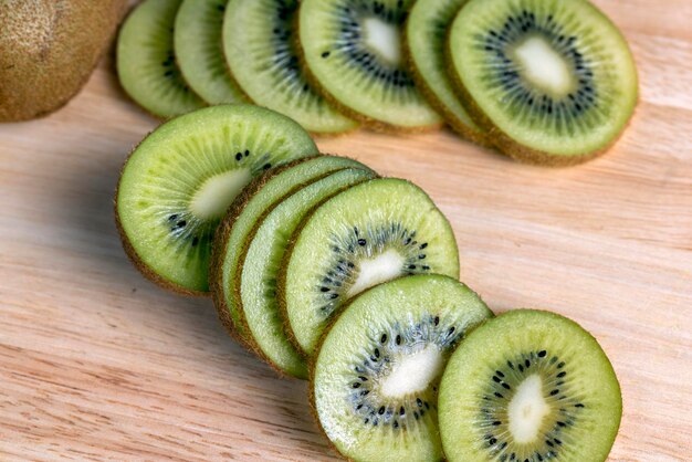 Sliced green kiwi fruit on a wooden board