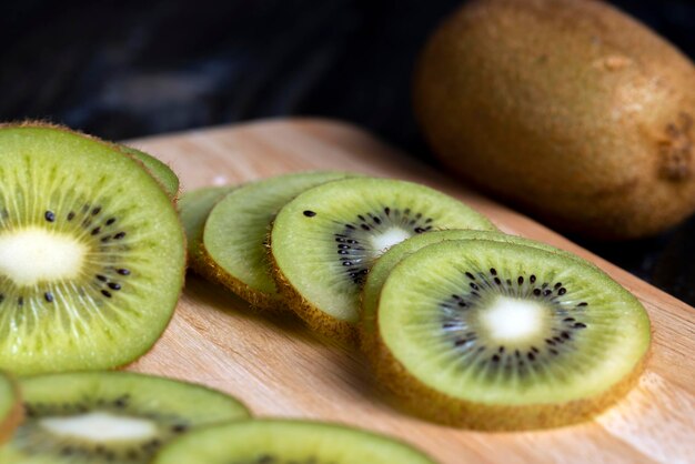 Sliced green kiwi fruit on a wooden board