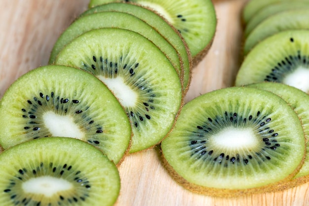 Sliced green kiwi fruit on a wooden board