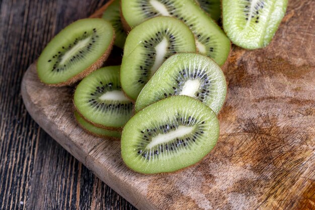 Sliced green kiwi fruit on a wooden board