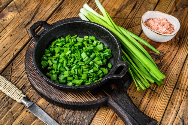 Sliced Green onions in a pan. wooden background. Top view.