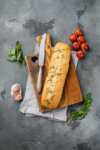 Sliced grilled bread with garlic and herbs set, on gray stone table background, top view flat lay, with copy space for text