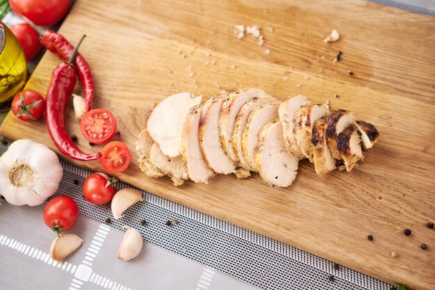 Sliced grilled chicken breast on wooden cutting board