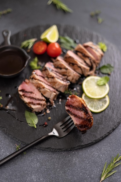 Sliced grilled cooked piece of tuna fillet on black stone serving board