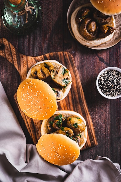 Sliced grilled mushrooms in burger buns on a wooden board top and vertical view