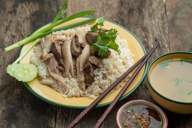 スライスしたハイナンスタイルの鶏肉と肝臓を木製のテーブルにマリネしたご飯と一緒に