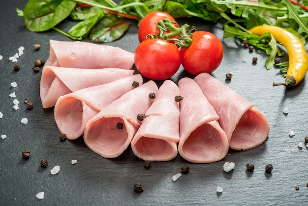 Sliced ham sausage on a stone background