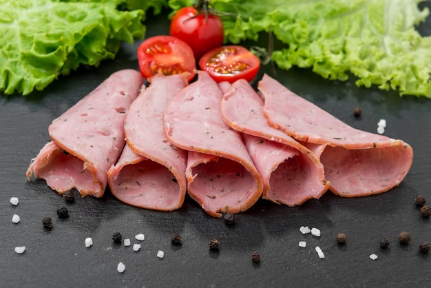 Sliced ham sausage on a stone surface