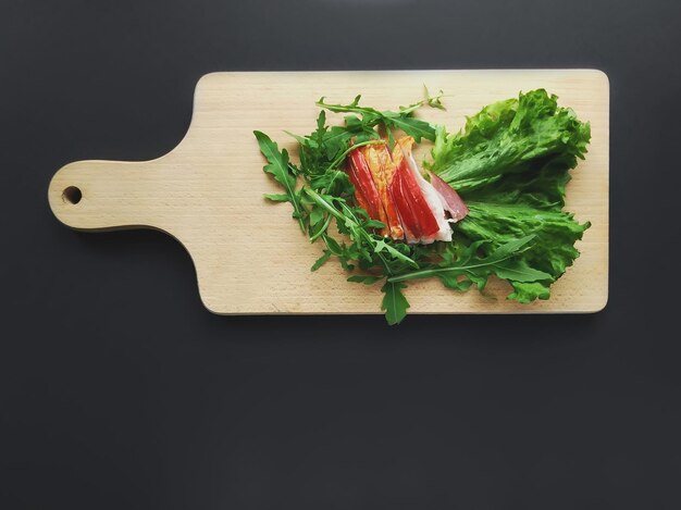 Sliced ham with fresh green lettuce leaves on a cutting board