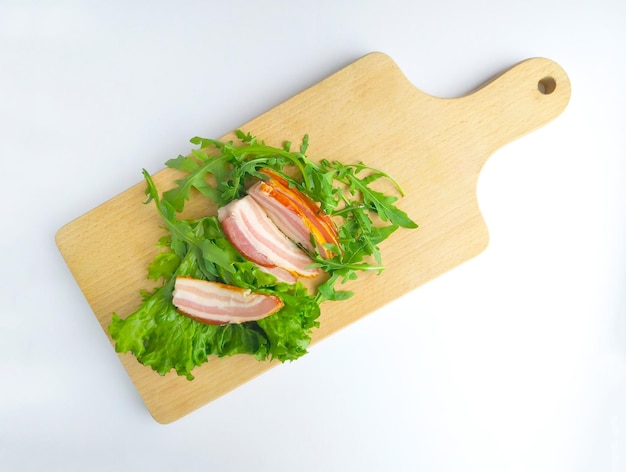 Sliced ham with fresh green lettuce leaves on a cutting board