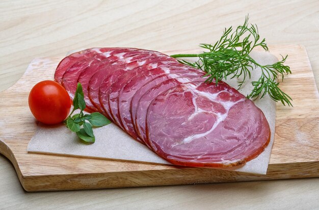 Sliced Ham with herbs on the wood background