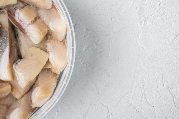 Sliced herring in oil marinated, on white background, top view flat lay with copy space for text