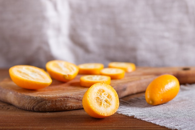 Sliced kumquats on a wooden kitchen board 