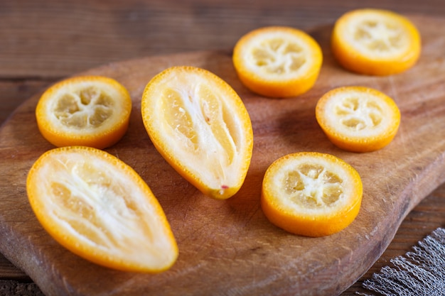 Sliced kumquats on a wooden kitchen board 