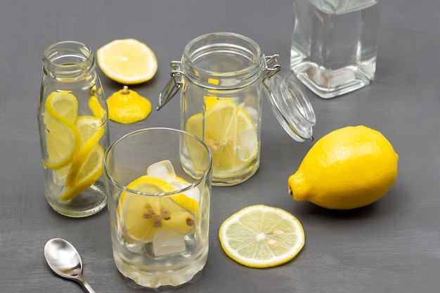 Нарезанный лимон в стакане и в банке с водой в бутылках