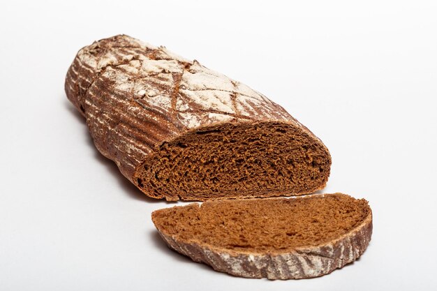 Sliced loaf of black rye bread with cuts from a knife on top of it and sprinkled with white flour isolated on a white background Healthy eating concept