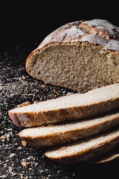 Sliced loaf of dark homemade bread dusted with flour