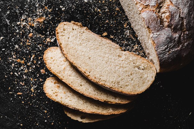 Sliced loaf of dark homemade bread dusted with flour