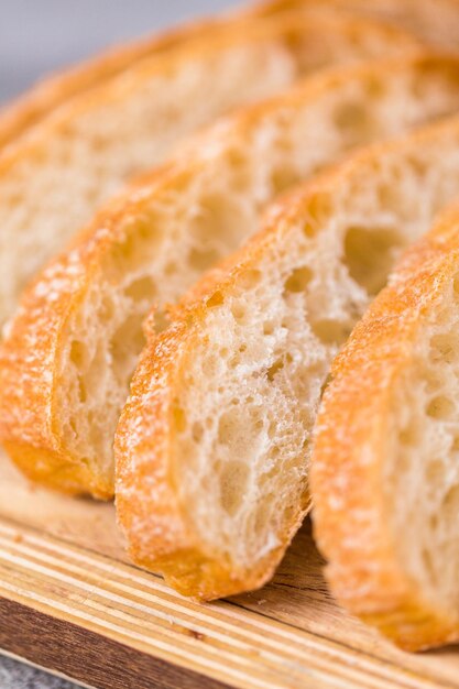 Sliced loaf of freshly baked ciabatta bread on gray table.