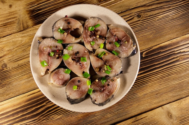 Sliced mackerel with spices on wooden table. Salted scomber on a plate