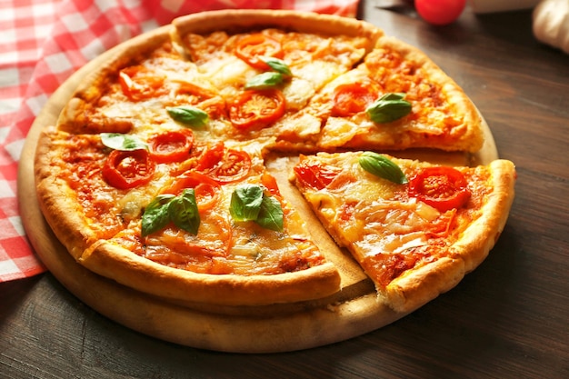 Sliced Margherita pizza on wooden background