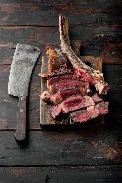 Sliced medium rare grilled Beef steak set tomahawk cut on wooden serving board on old dark wooden table background with copy space for text