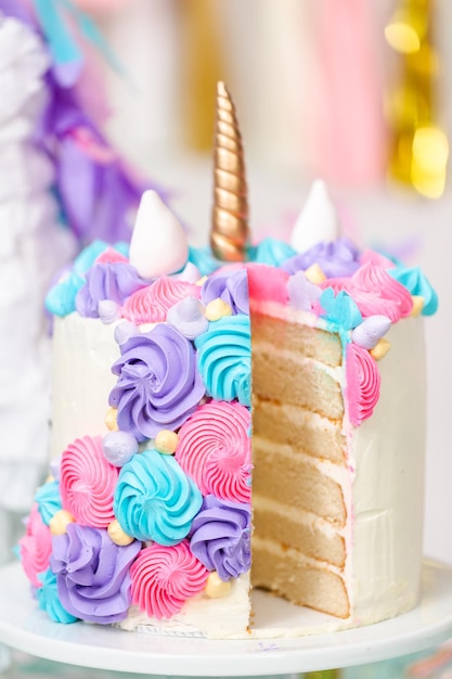 Sliced multilayer unicorn cake on cake stand at the little girl birthday party.