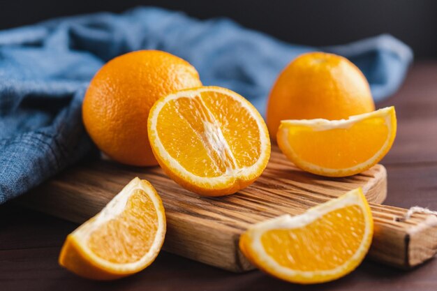 Фото Нарезанные апельсины фрукты рядом с джинсовой тканью на деревянной доске апельсиновые сочные фрукты цитрусовые минимальная концепция