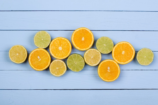 Photo sliced oranges lemons limes on blue wooden boards copy space