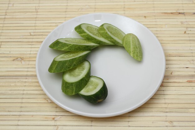 하얀 접시에 얇게 썬 타원형 모양의 신선한 오이 Cucumis sativus