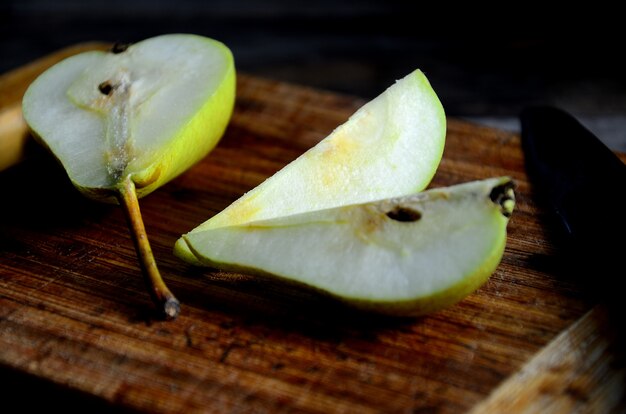 Sliced pear on a kitchen board and knife on a rustic table.