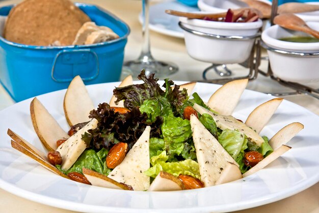 Sliced pear salad with cheese and caramelized almonds fresh green salad on restaurant table