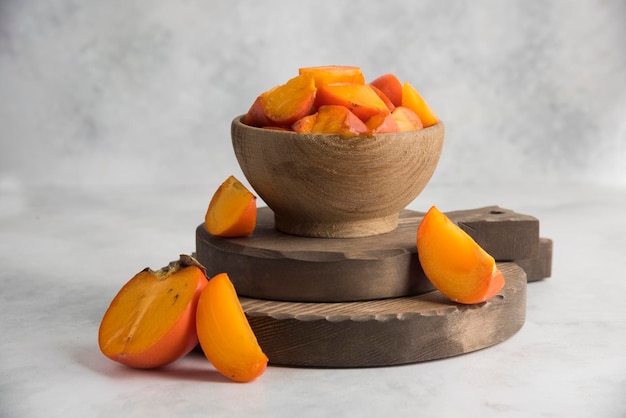 Photo sliced persimmons on wood cutting board