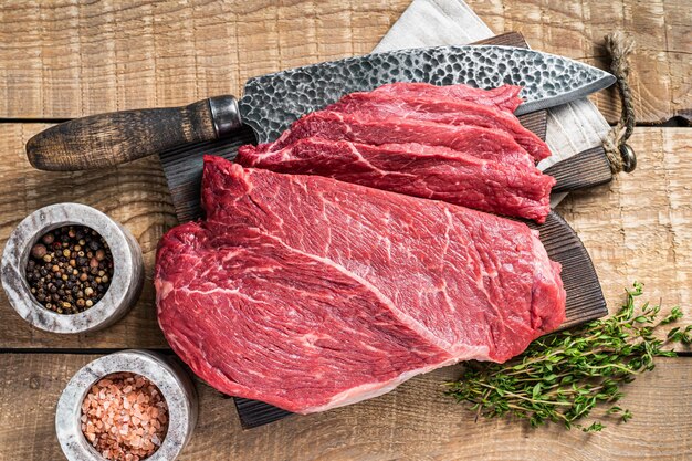 Sliced piece of marble raw beef meat on wooden cutting board. wooden background. Top view.