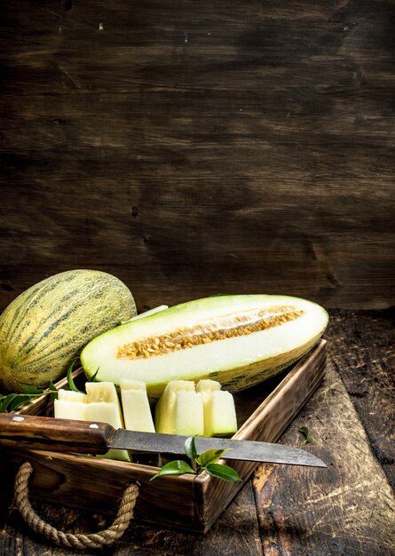 Sliced pieces of ripe melon on an old tray on a wooden background