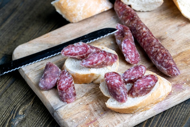 Sliced pieces of sausage from meat are lying on a cutting board pork meat with bacon is dried and withered the meat is ready for eating