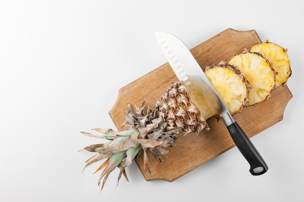 Sliced pineapple slices with a knife on a kitchen board  