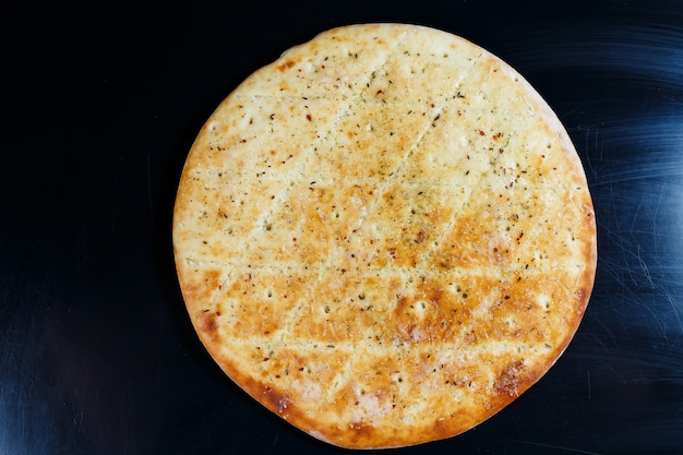 Pizza a fette su uno sfondo di pietra nera, vista dall'alto. focaccia appena sfornata con formaggio
