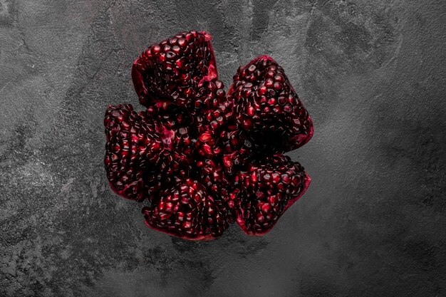 Sliced pomegranate fruit on a dark background, top view