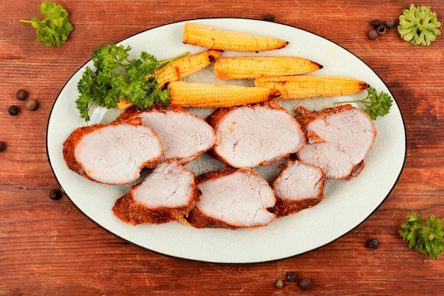 Sliced pork tenderloin grilled with corn on rustic wooden table Baked meat Top view