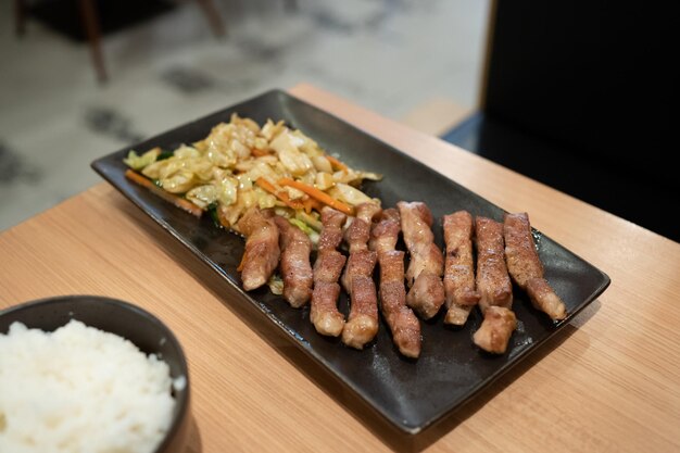 검은 접시에 데리야끼 일본 소스를 얹은 얇게 썬 돼지고기 그릴이나 요리를 위한 신선한 고기