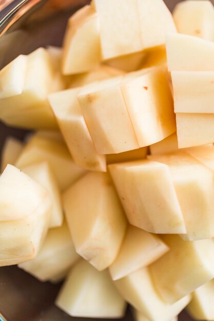 Sliced potatoe in a glass mixing bowl for cooking borscht.