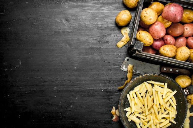 Sliced potatoes in an old frying pan. On the black chalkboard.