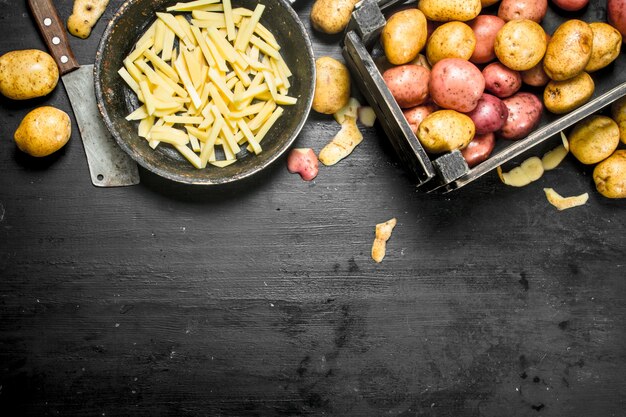 Sliced potatoes in an old frying pan. On the black chalkboard.