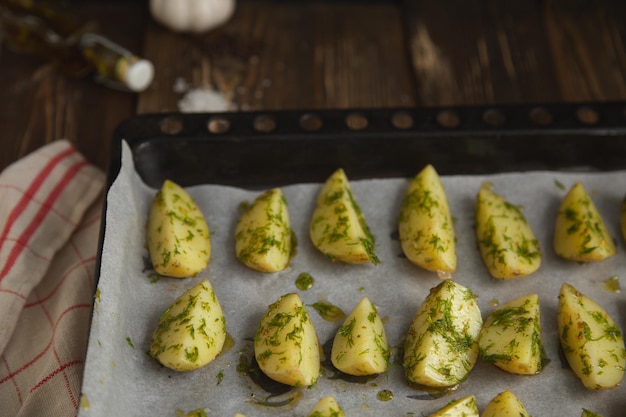 sliced potatoes with spices and dill on a baking sheet top view